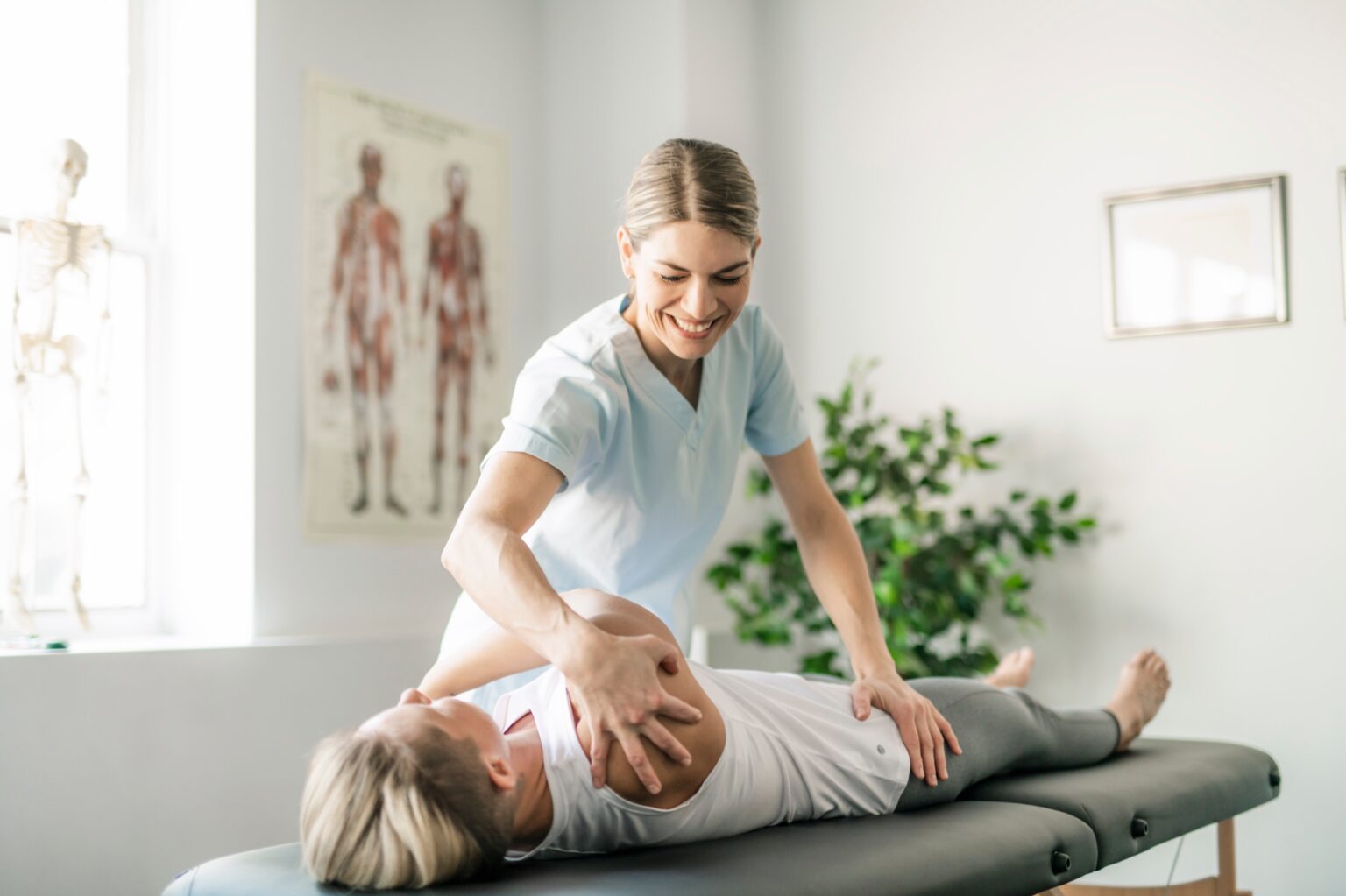 Therapeutin behandelt eine auf der Liege liegende Patientin