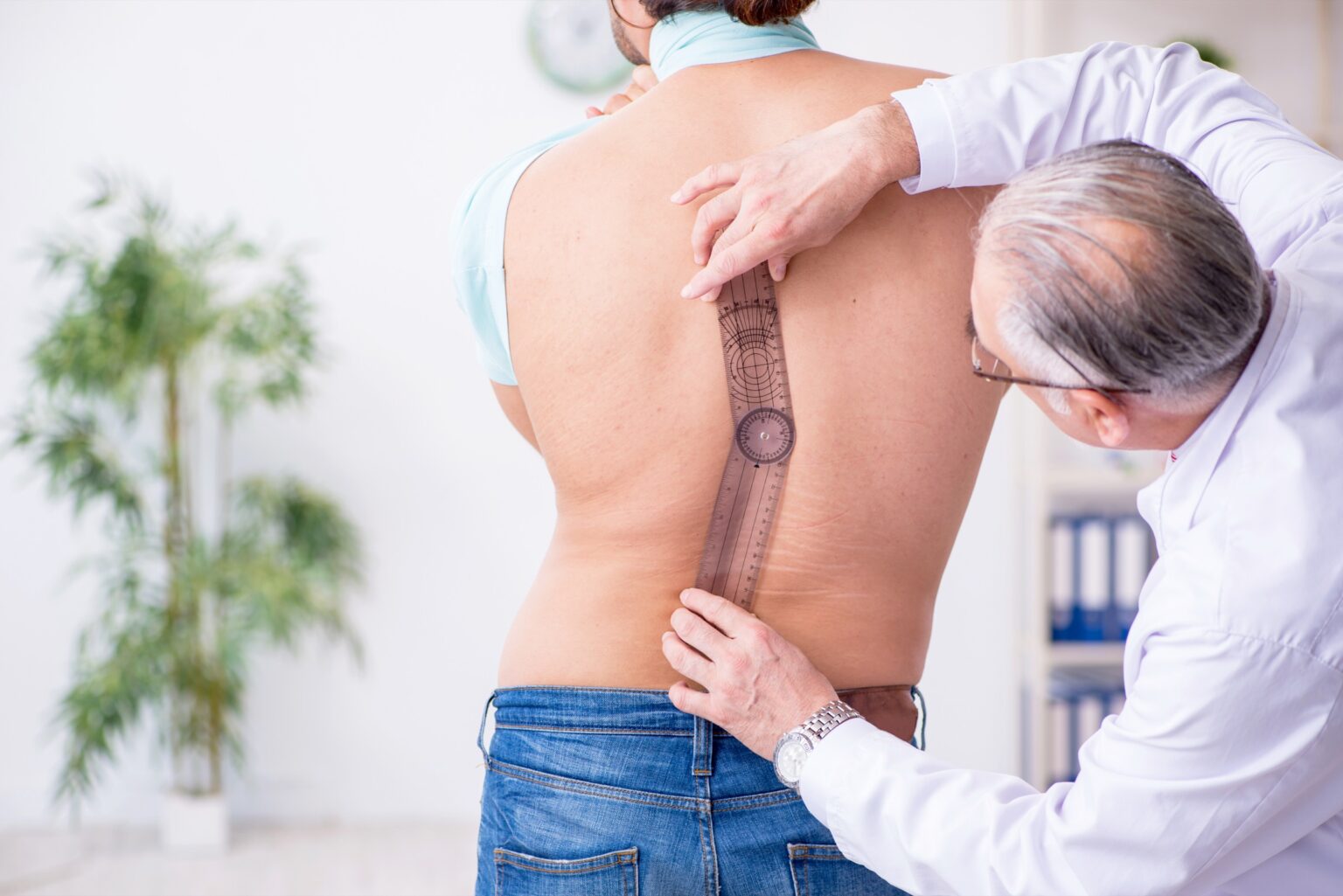 Arzt misst mit einem Messinstrument die Wirbelsäule eines Patienten